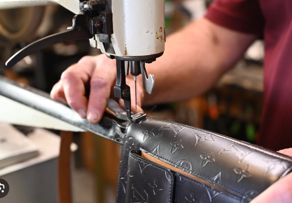 Craftsman stitching leather on an industrial sewing machine at Jacob's Shoe Repair workshop